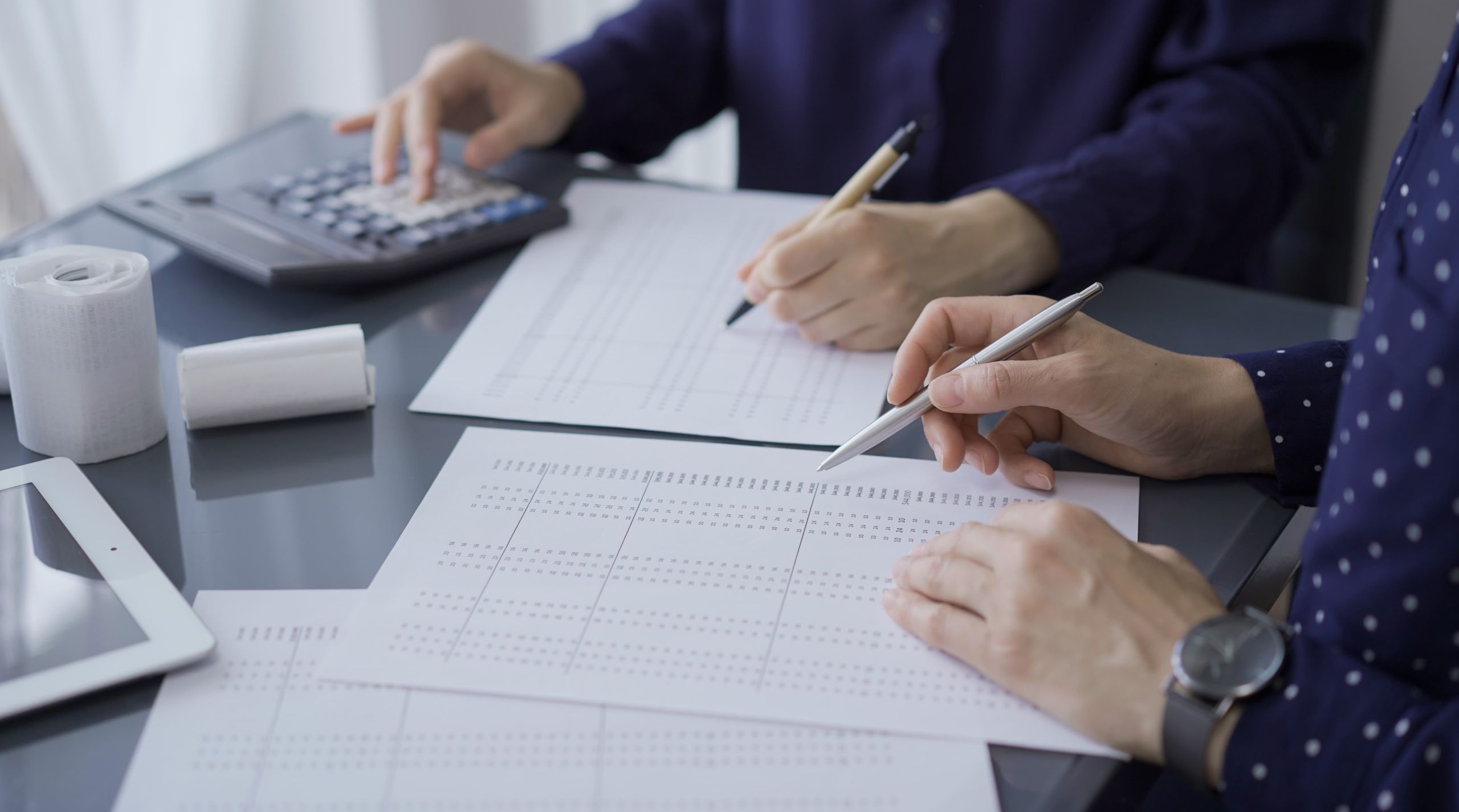 Small business owner calculating taxes with paperwork calculator and laptop showing financial stress