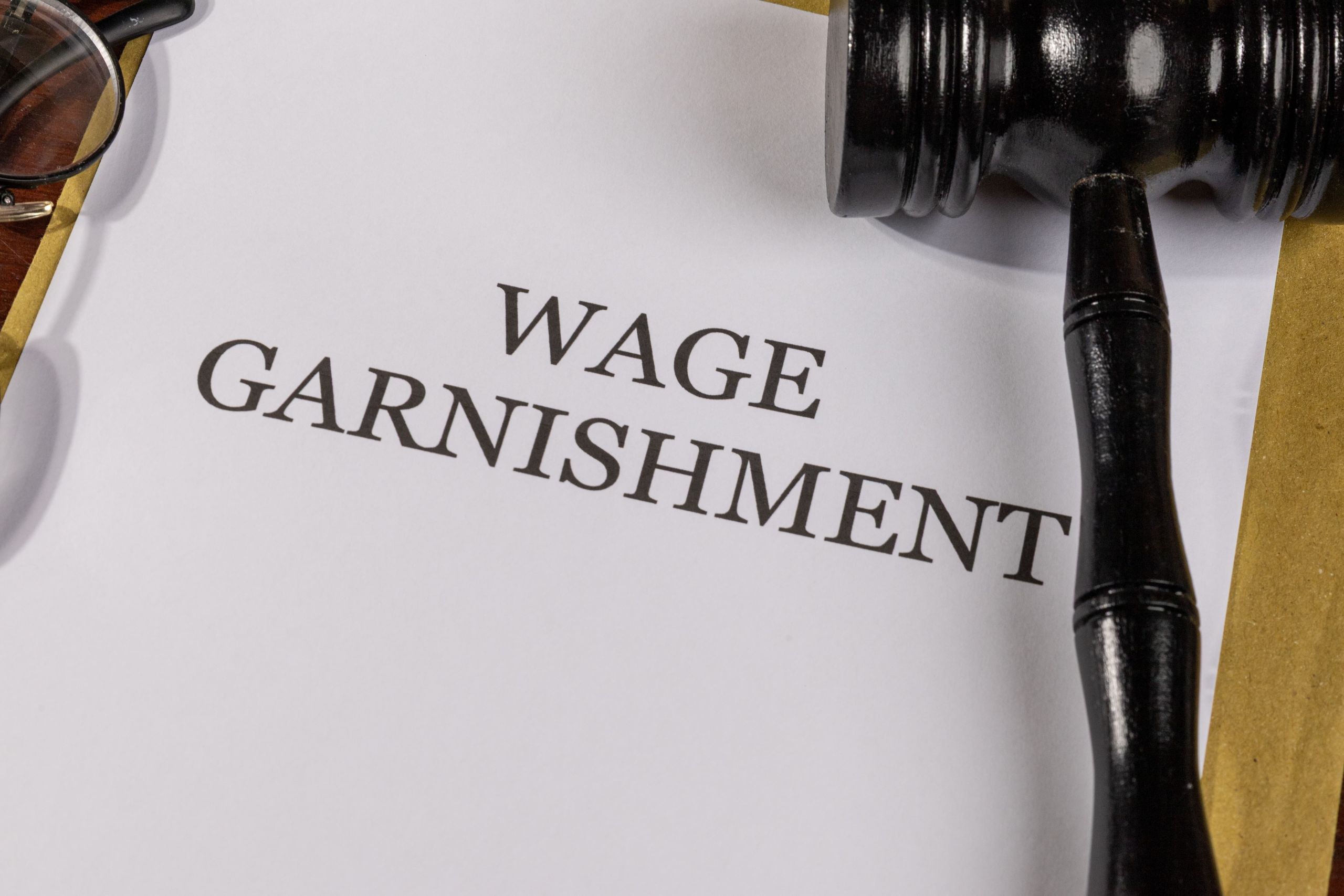 Legal document titled "Wage Garnishment" next to a gavel, illustrating how the IRS can garnish wages when a taxpayer owes more than $10,000 in unpaid tax debt